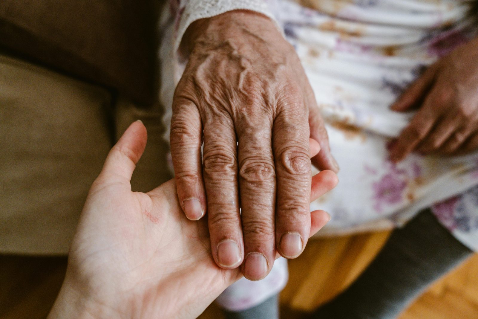 A caregiver’s hand holding a resident’s hand